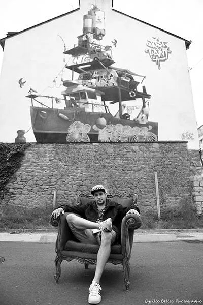 Homme assis devant une fresque murale en noir et blanc.