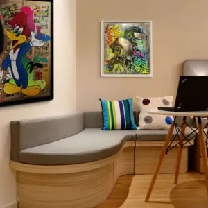 Chambre avec affiches, canapé gris et ordinateur portable.