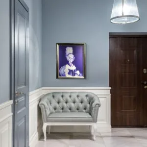 Hall élégant avec canapé gris et tableau surréaliste.