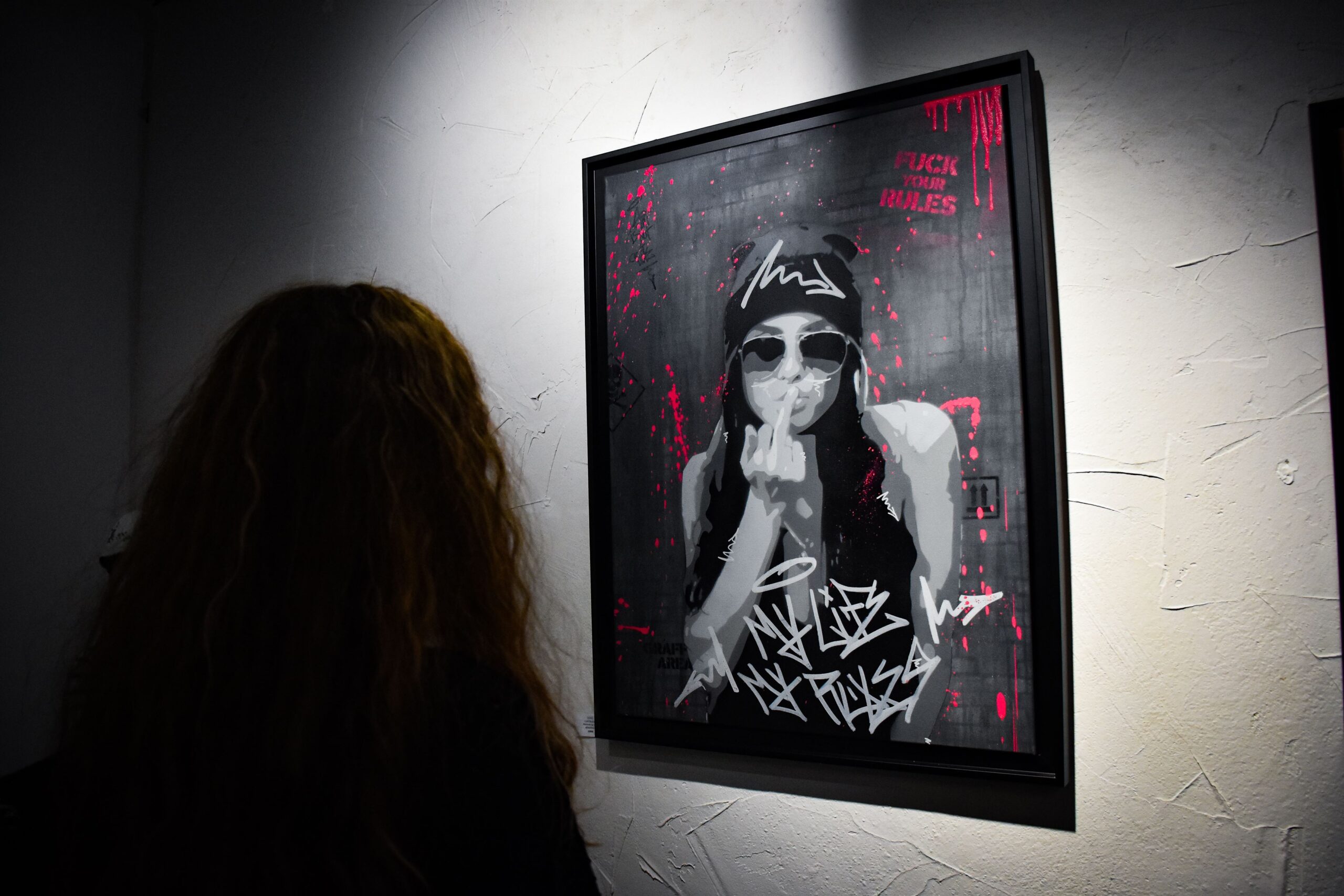 Femme observant une œuvre d'art rebelle en galerie.