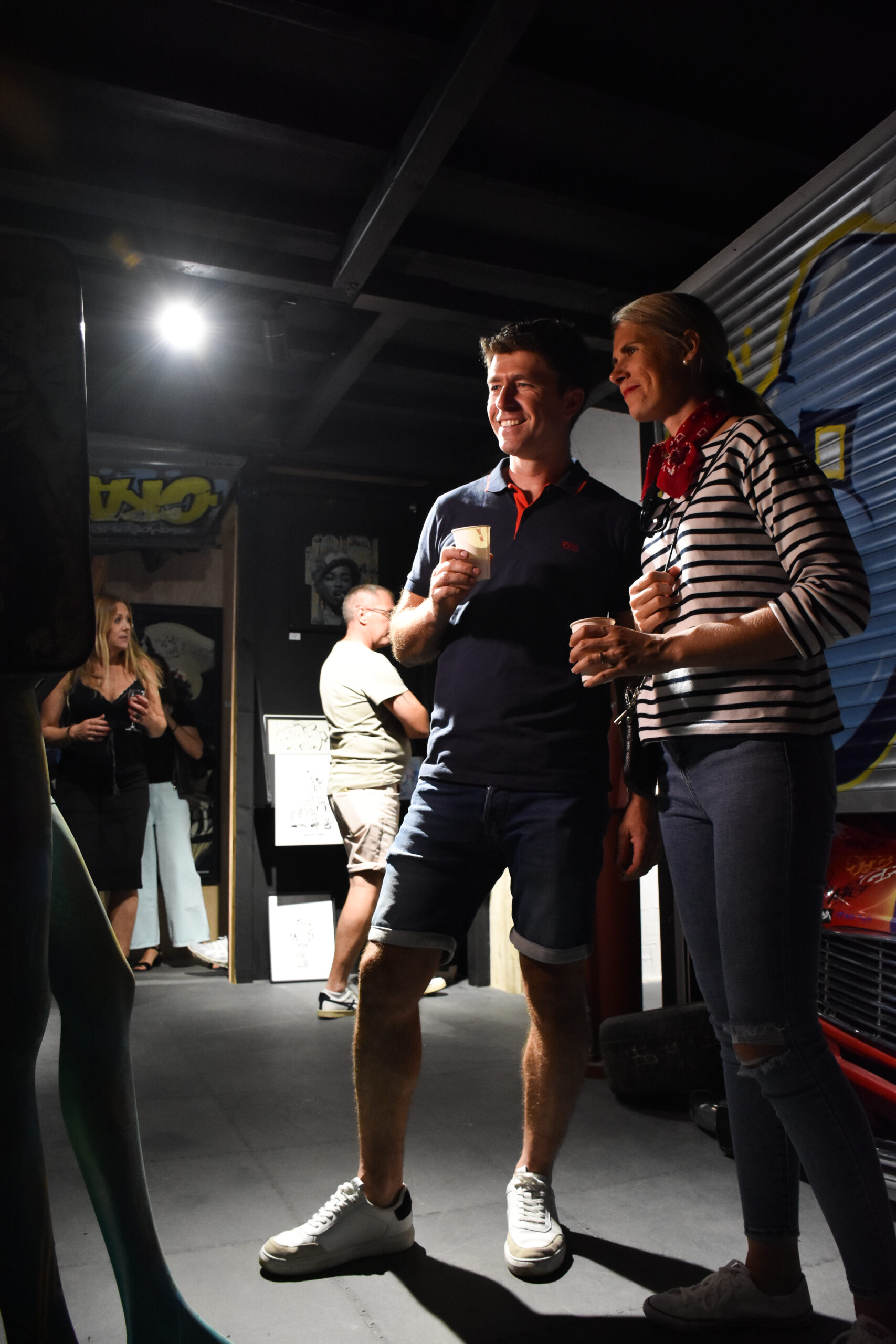 Couple souriant avec café dans un garage stylisé.