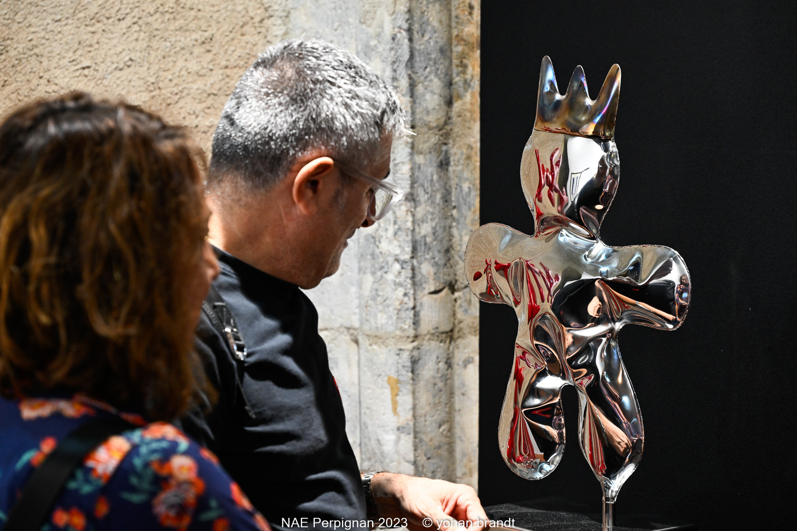 Visiteurs observant une sculpture métallique moderne à Perpignan.