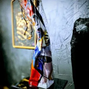 Statue en verre coloré sur socle noir.